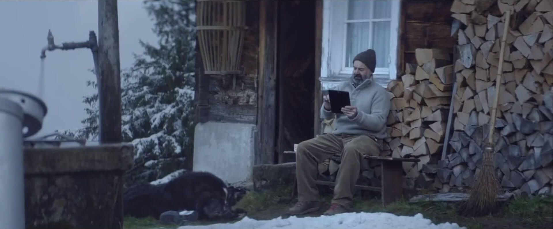 Mann sitzt vor einem Haus und nutzt eine mobile App
